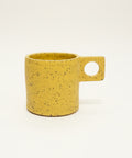 Yellow speckled mug on a wooden surface with a blurred background
