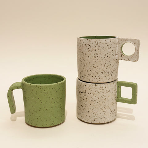 Two ceramic mugs on a wooden surface with an Apple product in the background