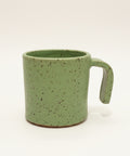 Green speckled mug on a wooden desk