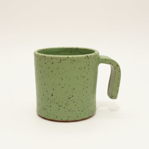 Green speckled mug on a wooden desk