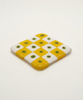 Yellow and white checkered object on a wooden surface with a blurred background