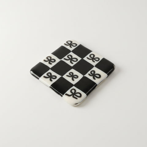 Black and white checkered coaster on a wooden surface