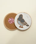 Wooden desk with decorative coasters featuring bird designs and a small pink object.