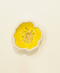 Decorative ring dish with yellow center and white border on a wooden surface