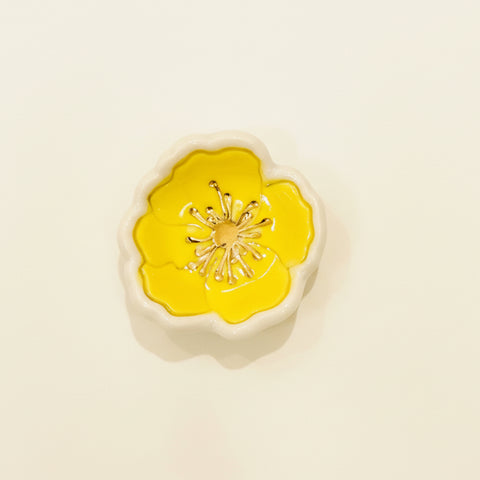 Decorative ring dish with yellow center and white border on a wooden surface
