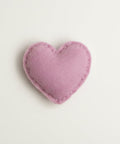 Heart-shaped catnip toy in clear packaging with a label on a textured fabric background