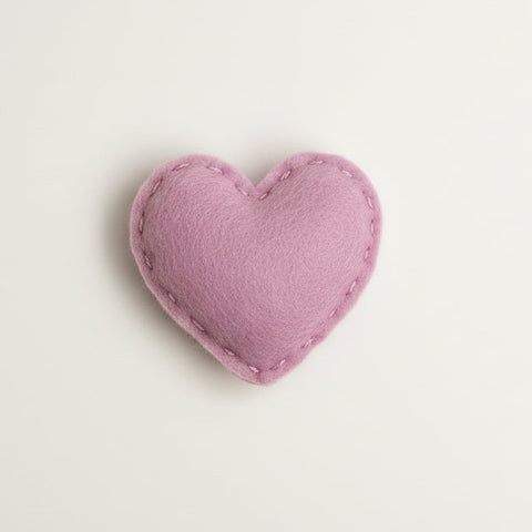 Heart-shaped catnip toy in clear packaging with a label on a textured fabric background