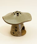 Ceramic mushroom-shaped incense burner on a beige background