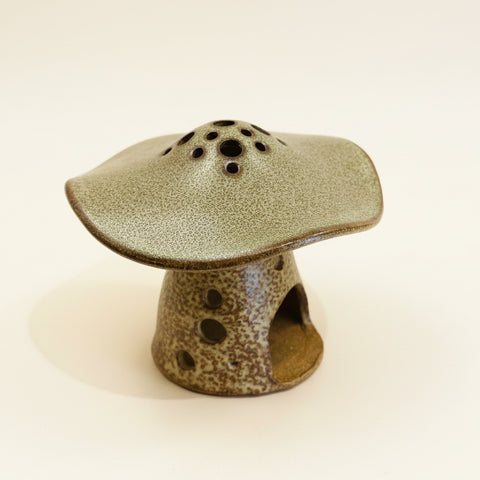 Ceramic mushroom-shaped incense burner on a beige background