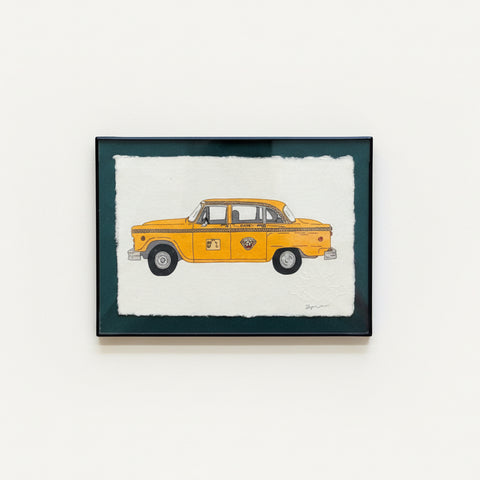 Framed artwork of a yellow taxi on a wooden floor