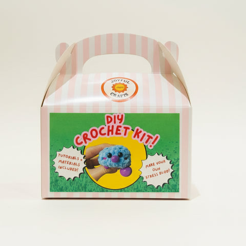 DIY crochet kit packaging on a wooden surface with a blurred background