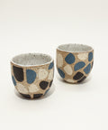 Two ceramic cups with polka dot pattern on a wooden surface