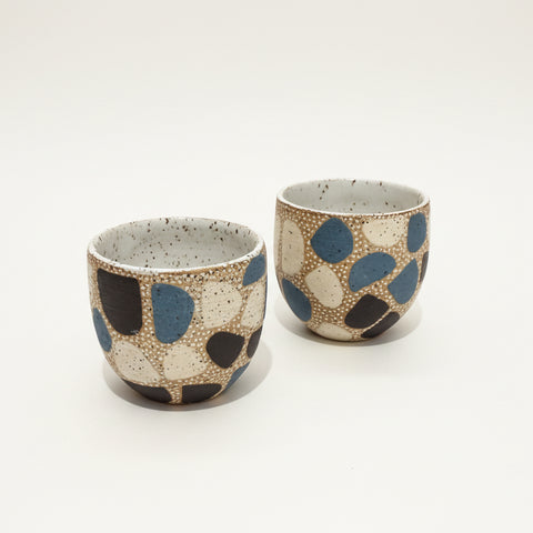 Two ceramic cups with polka dot pattern on a wooden surface