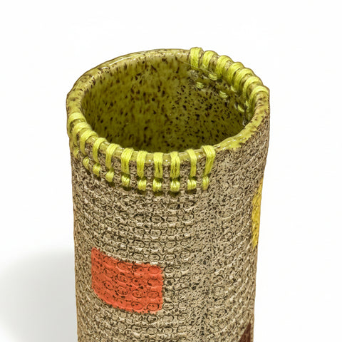 Cylindrical ceramic vase with textured surface and colorful accents.