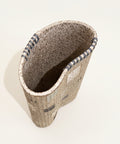 Speckled ceramic vase in a kidney shape with hand sewn embellishments.