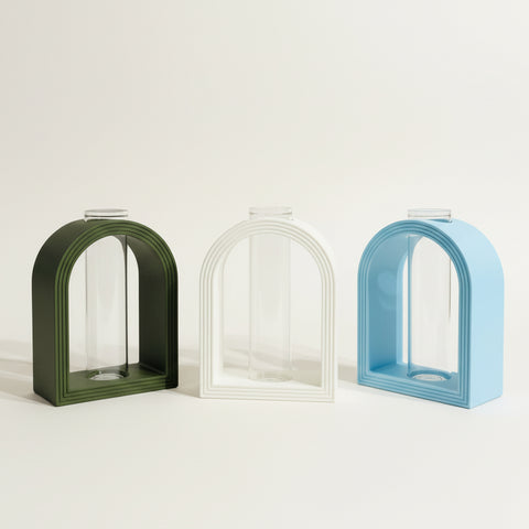 Three colorful jewelry display stands on a wooden surface with a neutral background.