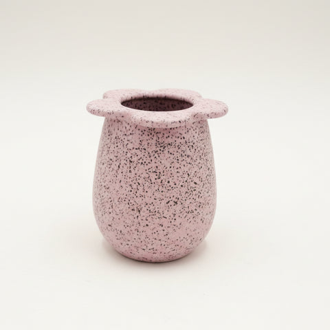 Speckled ceramic vase with flower-shaped rim on a wooden surface