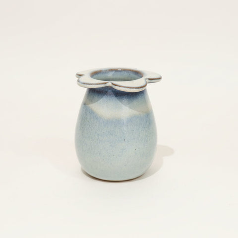 Small ceramic jar with a blue glaze and white handle on a light gray background