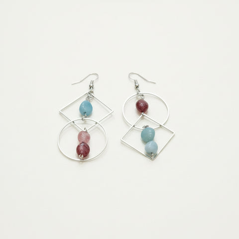 Pair of earrings with geometric designs and colorful beads on a wooden surface