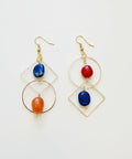 Gold earrings with blue and orange stones on a wooden surface