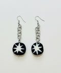 Black and white star-shaped earrings on a wooden surface