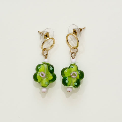 Pair of green floral earrings on a wooden surface
