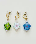 Three floral-themed earrings on a wooden surface