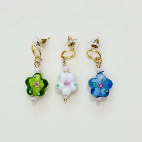 Three floral-themed earrings on a wooden surface