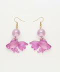 Purple fish-shaped earrings on a wooden surface