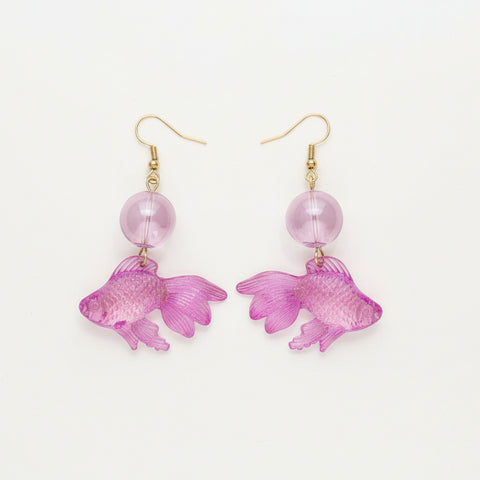 Purple fish-shaped earrings on a wooden surface