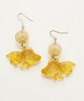 Gold fish-shaped earrings with clear beads on a wooden surface