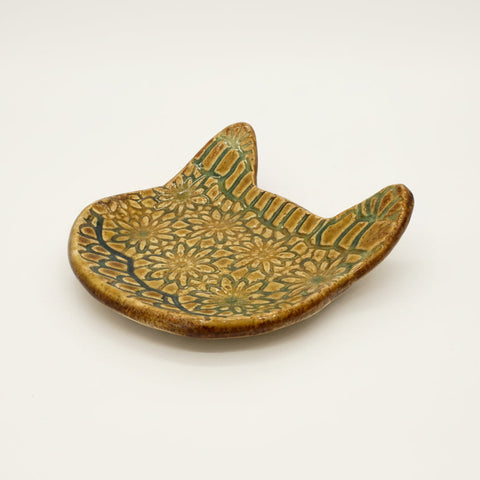 Ceramic cat-shaped dish with green floral patterns on a wooden surface
