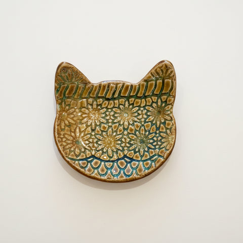 Ceramic cat-shaped dish with floral patterns on a wooden surface
