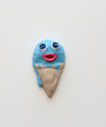 Ice cream cone-shaped wall art with blue face on a wooden table
