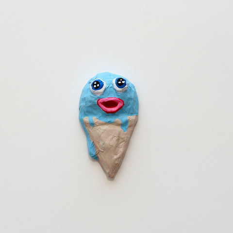 Ice cream cone-shaped wall art with blue face on a wooden table