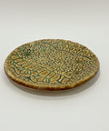 Ceramic plate with green and brown pattern on a wooden surface