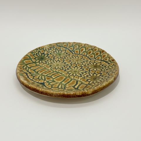 Ceramic plate with green and brown pattern on a wooden surface