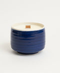 Blue ceramic candle with a wooden wick on a white background