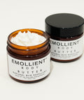Two jars of Emollient Body Butter on a wooden surface