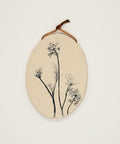 Oval-shaped wooden art piece with floral design on a wooden surface