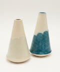 Two ceramic vases on a wooden table with a laptop in the background.