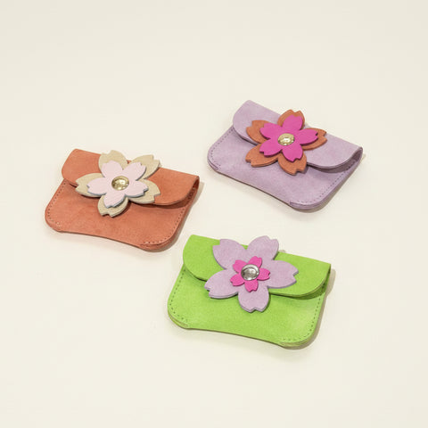 Three small pouches with floral designs on a wooden surface
