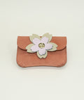 Small pink pouch with a floral design on a wooden surface