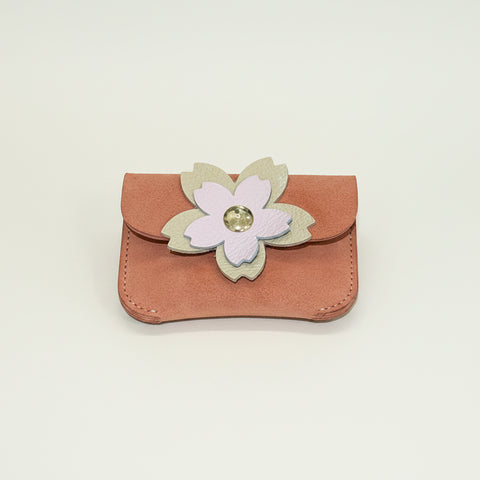 Small pink pouch with a floral design on a wooden surface