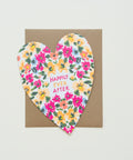 Heart-shaped card with floral design and 'Happily Ever After' text on a wooden surface