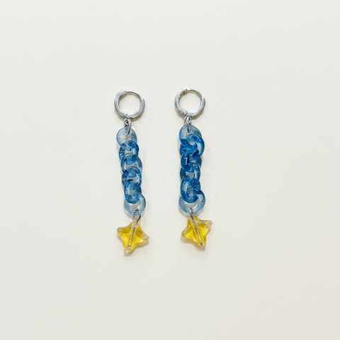 Pair of earrings with blue braided design and yellow star-shaped charms on a white background