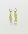 Pair of gold earrings with green gemstones on a wooden surface