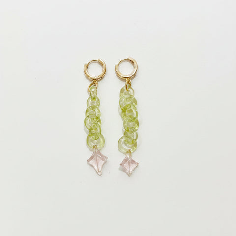 Pair of gold earrings with green gemstones on a wooden surface