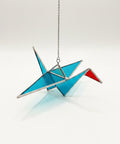 Colorful stained glass crane on a wooden surface with store interior in the background