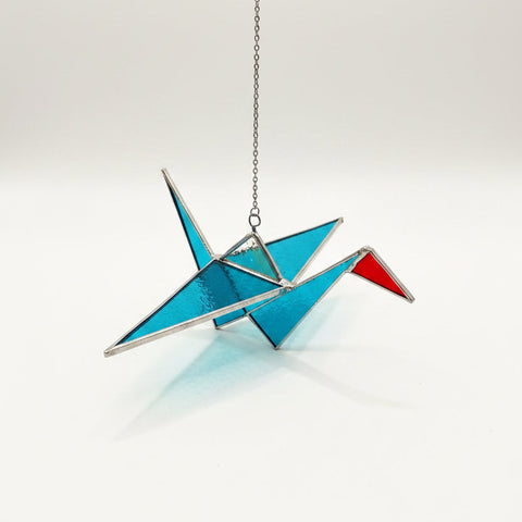 Colorful stained glass crane on a wooden surface with store interior in the background